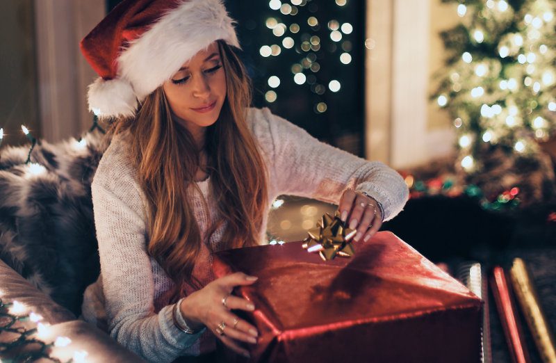 eine Frau öffnet ein Weihnachtgeschenk